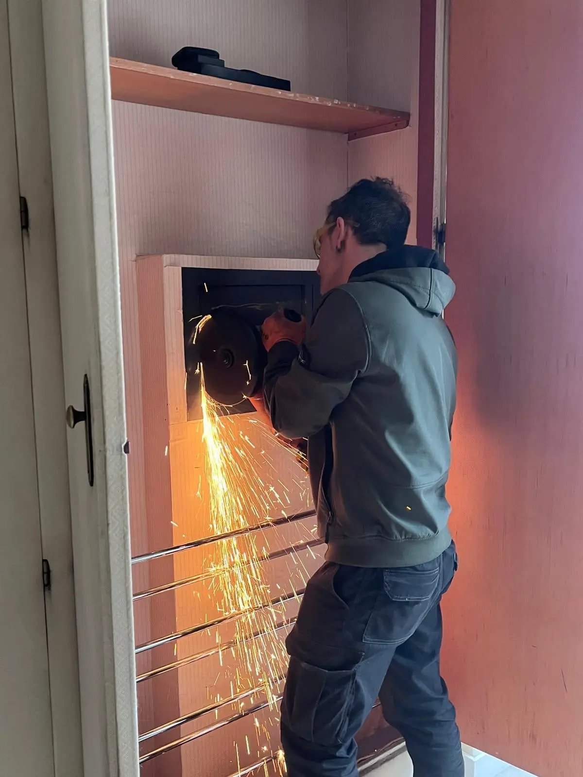 Iván abriendo con una radial una caja fuerte empotrada en un armario, entre chispas