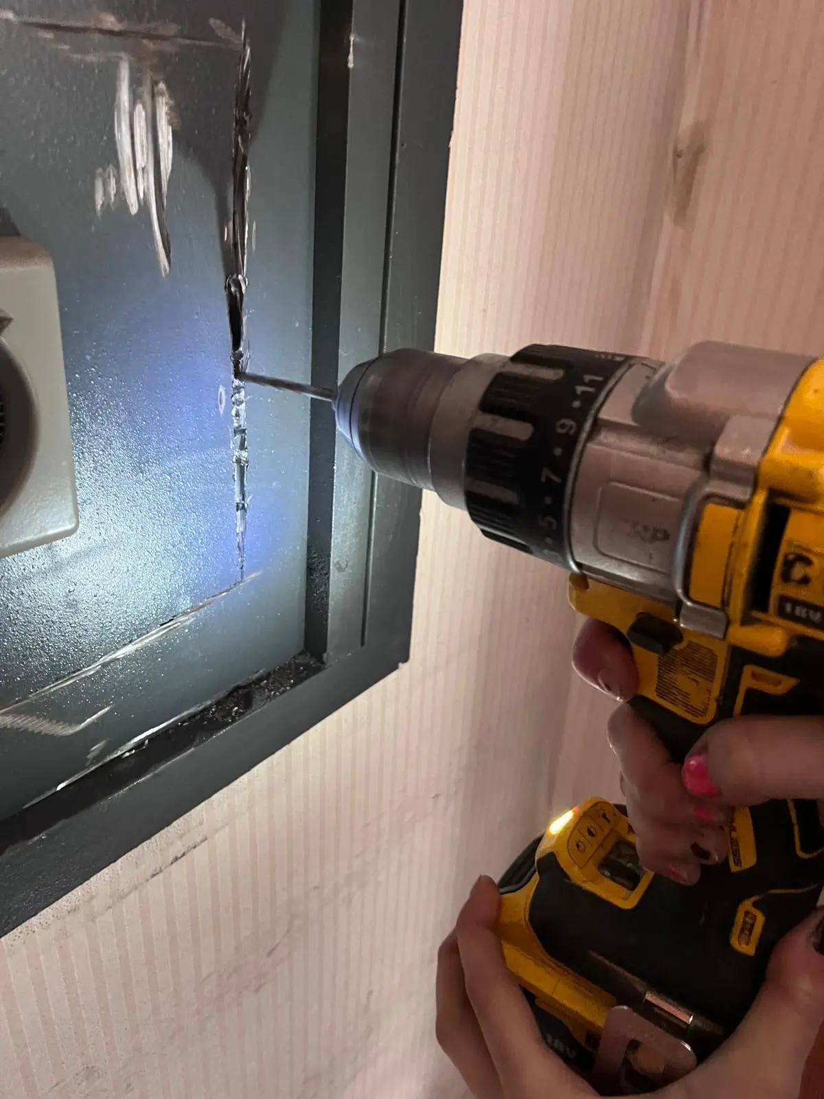 Taladro perforando la puerta de una caja fuerte empotrada para abrirla