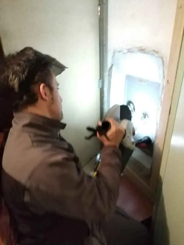 Iván trabajando con una herramienta en una caja fuerte empotrada en la pared