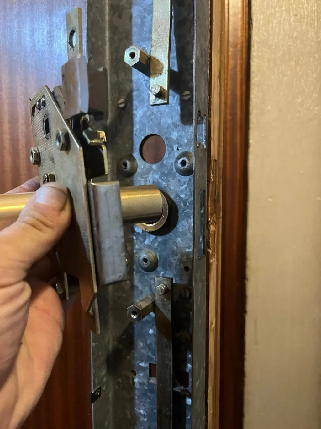 Mano sujetando una cerradura multipunto en el canto de una puerta