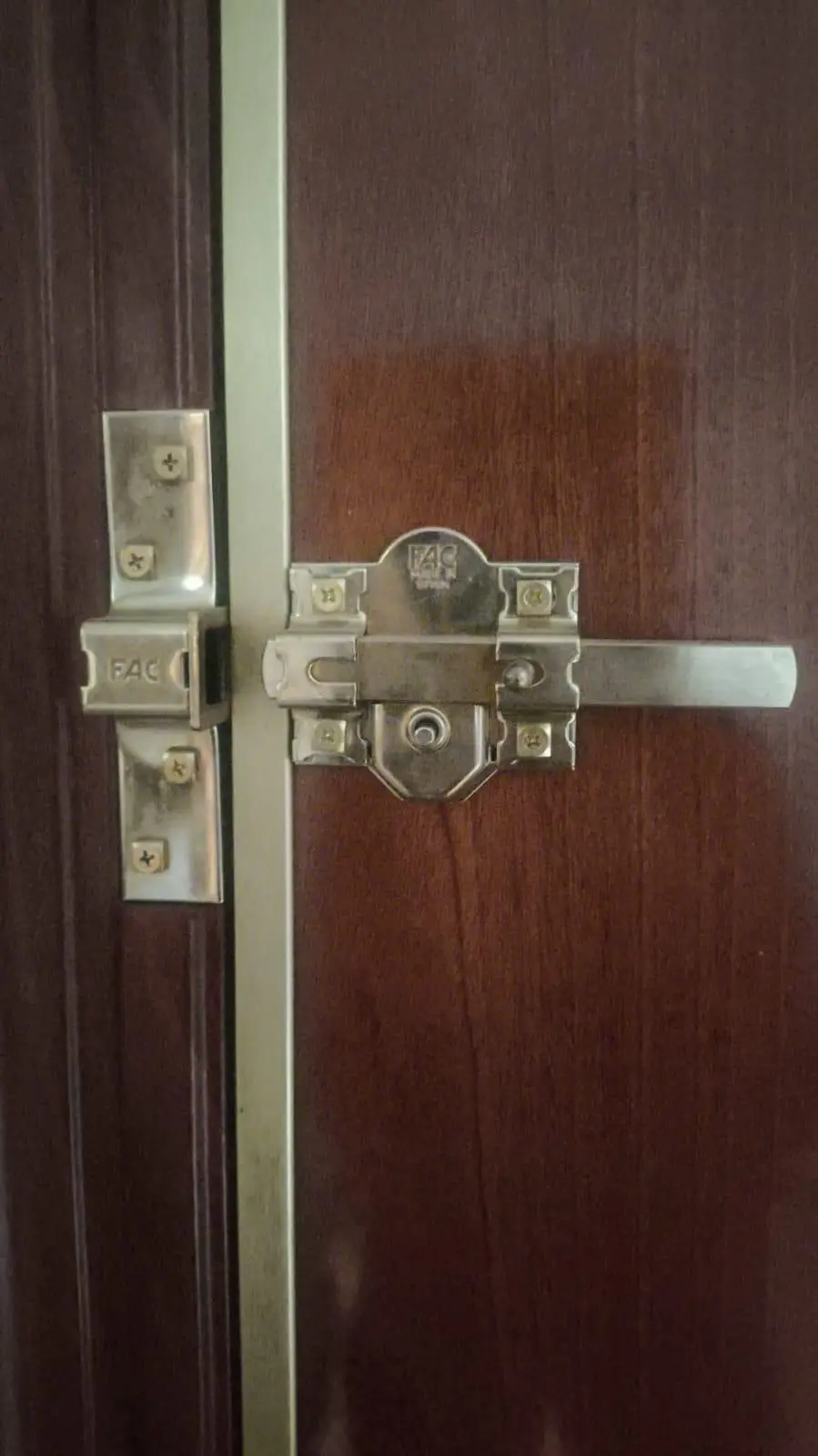 Cerrojo de seguridad FAC con su cerradero, instalado en una puerta de madera