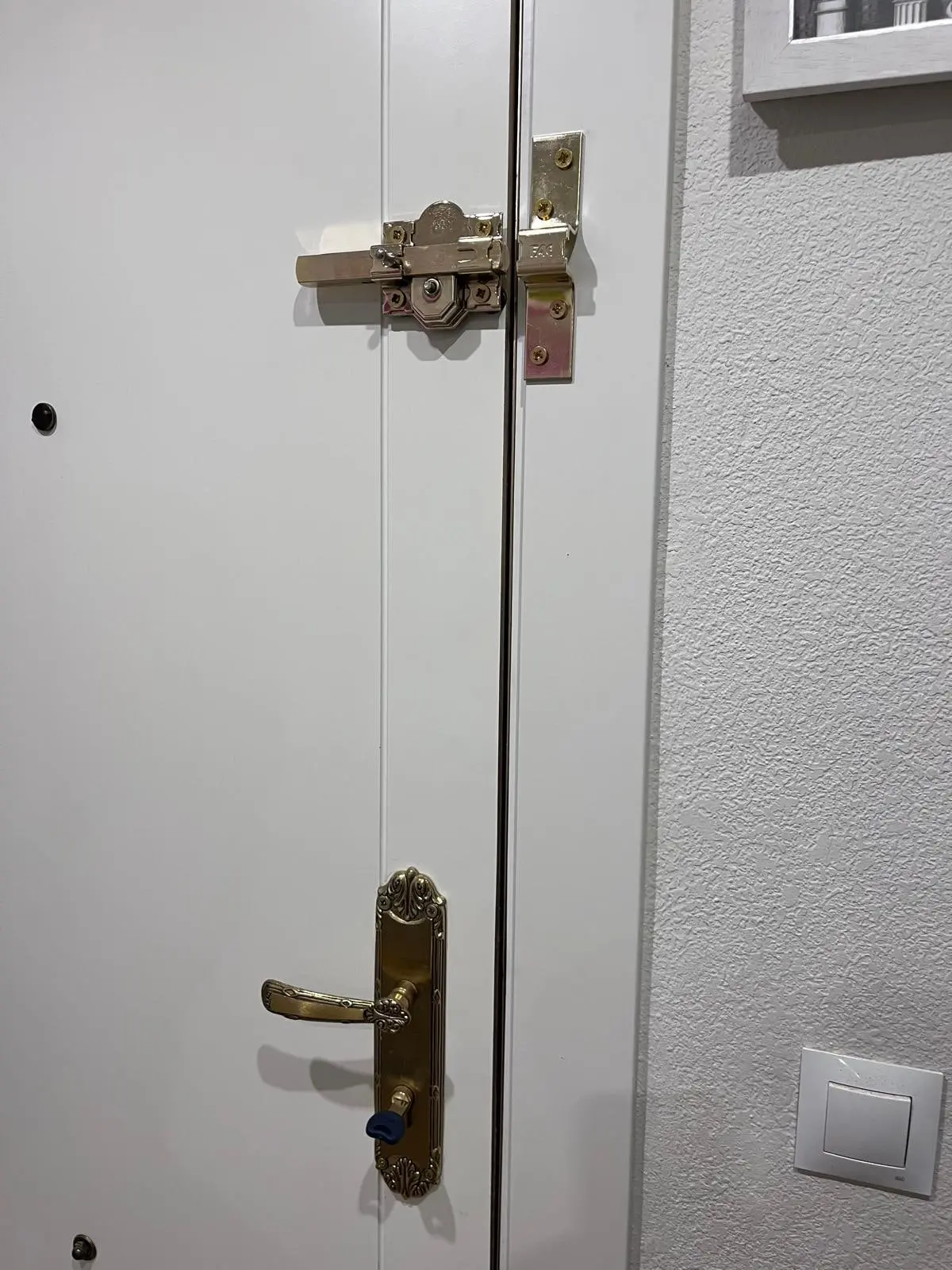 Cerrojo de seguridad FAC instalado en una puerta blanca, junto a la manilla