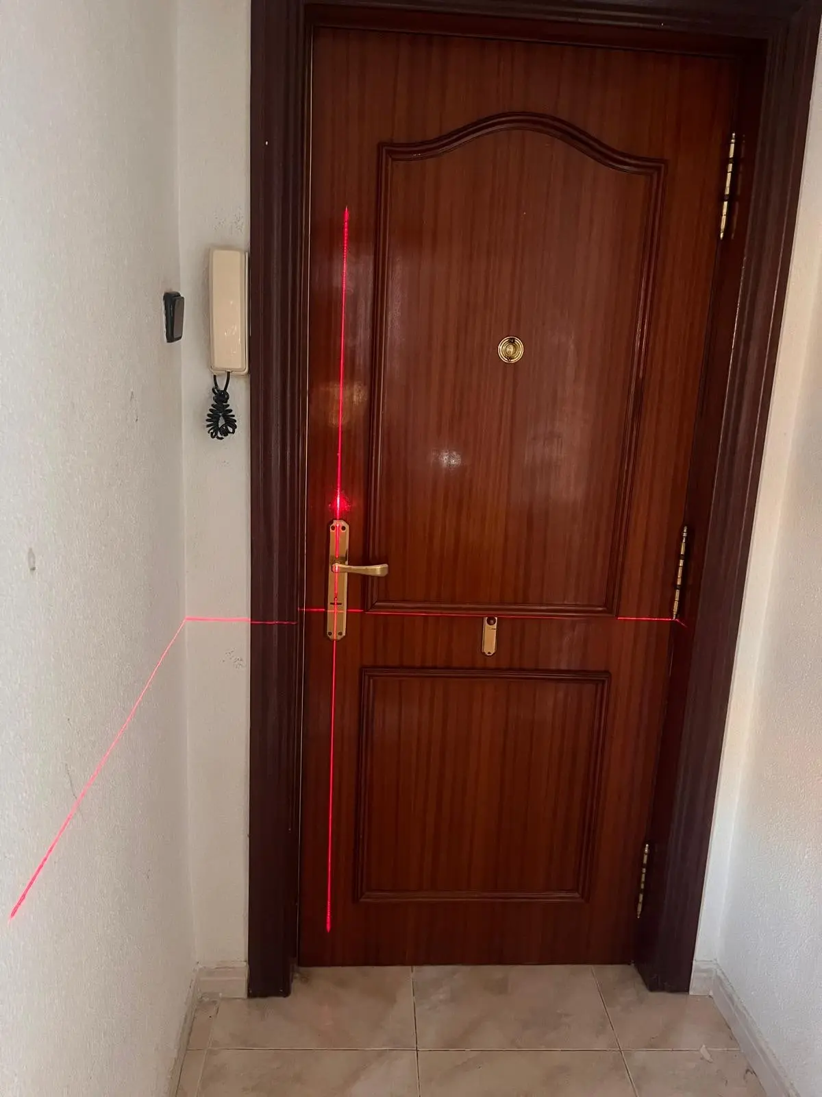 Puerta de entrada de un piso marcada con un nivel láser antes de instalar un cerrojo de seguridad