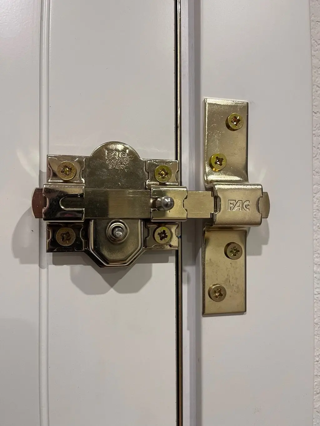 Cerrojo de seguridad dorado recién instalado en una puerta blanca