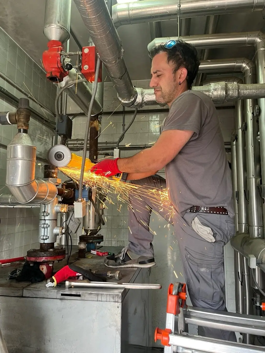 Iván cortando con una radial en la cocina de un local, con chispas