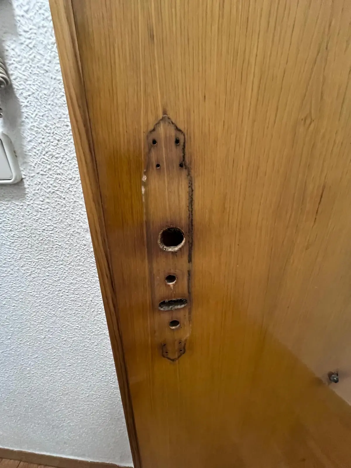 Puerta sin la manilla ni la cerradura de gorjas: se ven la marca de la placa y los agujeros antiguos