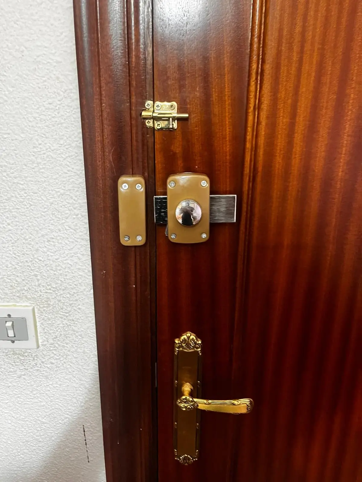Cerradura de sobreponer con su cerradero en el marco, en la puerta de una habitación de un piso compartido