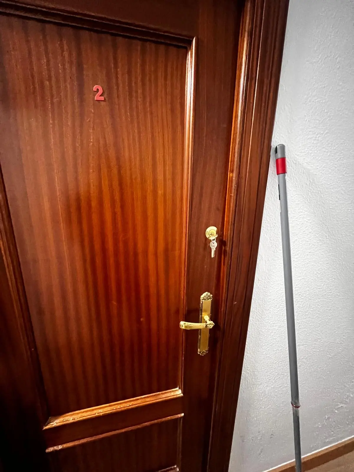 Puerta de la habitación número 2 de un piso compartido, con cerradura y llave