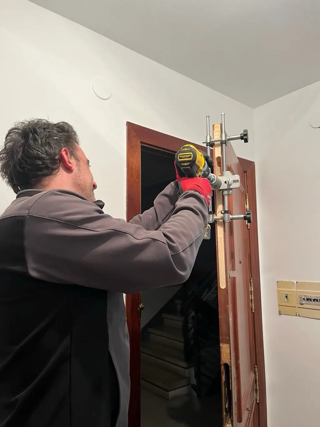 Iván instalando una cerradura con plantilla de taladro en la puerta de un piso